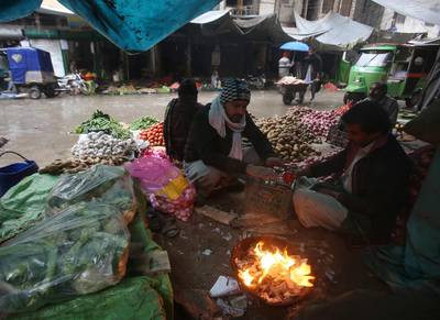 Pakistani vendors sit beside a fire to warm themselves in severe cold weather and rainfall, in Peshawar. AP Photo