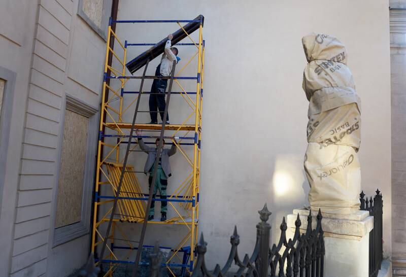 Workers remove scaffolding after covering a statue and windows to try to prevent damage in a Russian attack.