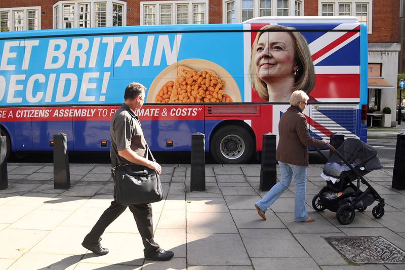 People walk past an image in central London of Ms Truss on the side of a protest bus calling for a citizens' assembly. Reuters