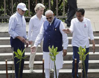 Indian Prime Minister Narendra Modi, centre right, Indonesian President Joko Widodo, right, Mr Biden and European Commission President Ursula von der Leyen plant mangroves. AFP
