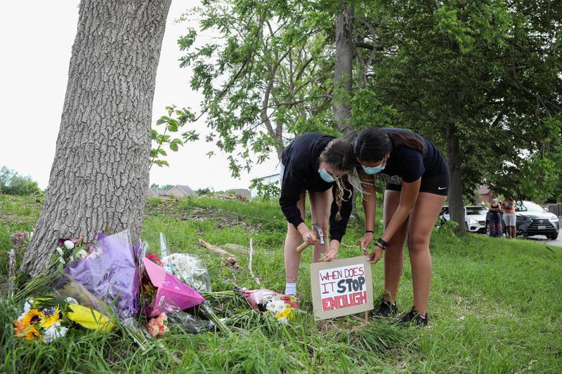 Clara Meagher, left, and Kelyalynn Detibeiro put up a sign at the scene in London, Ontario, Canada, where four of five members of a Muslim family were killed by what police say was a hit-and-run attacker. Reuters