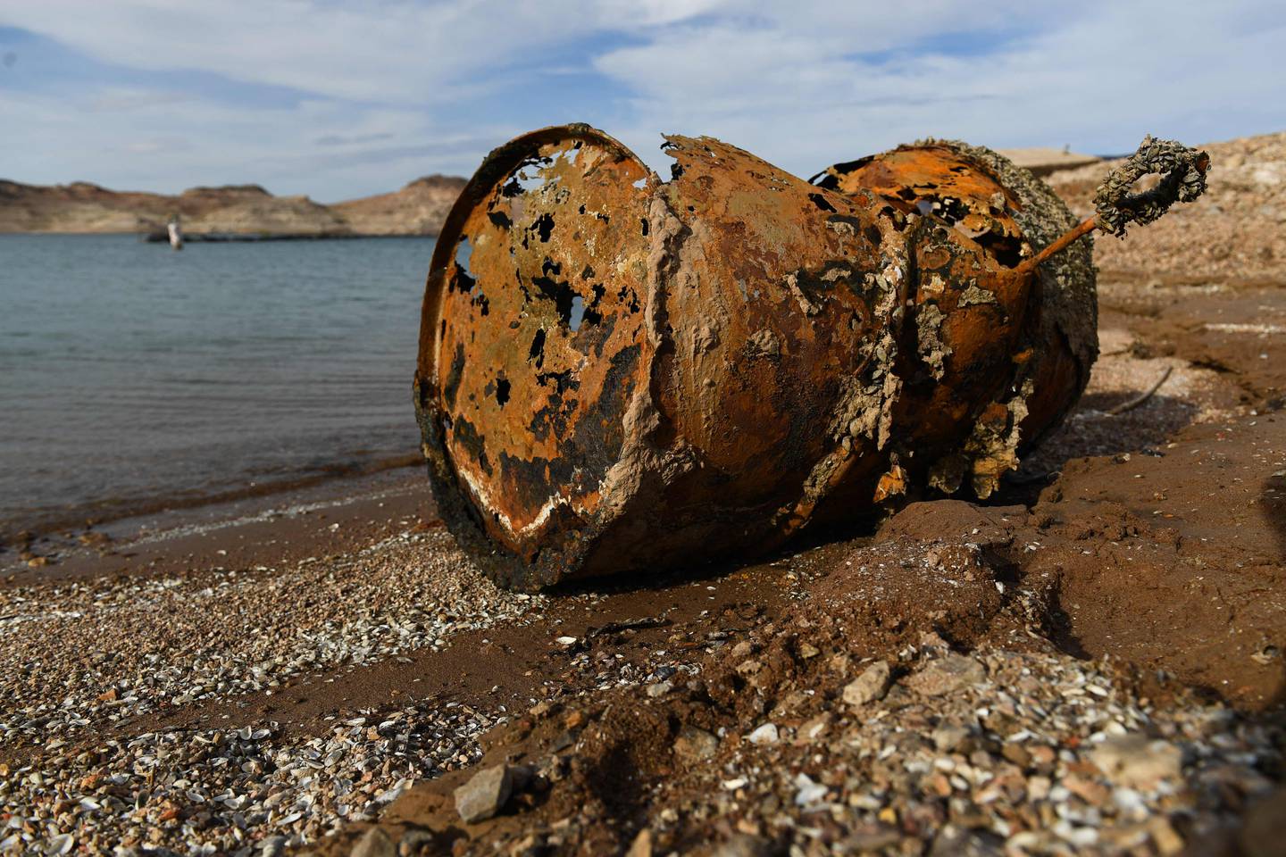 A rusted metal barrel, near the location of where a different barrel was found containing a human body, sits exposed on shore during low water levels due to the western drought at the Lake Mead Marina on the Colorado River. AFP
