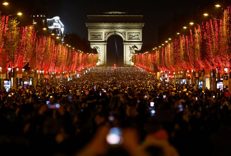 People attend New Year celebrations on the Champs-Elysees avenue as the traditional light show and fireworks have been cancelled due to the spread of the coronavirus disease (COVID-19) in Paris, France.