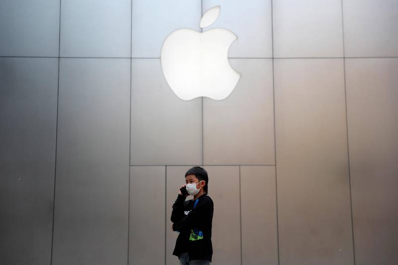 epa08347704 A boy wearing protective face mask uses mobile phone outside an Apple store at Sanlitun in Beijing, China, 07 April 2020.  Countries around the world are taking increased measures to stem the widespread of the SARS-CoV-2 coronavirus which causes the Covid-19 disease.  EPA/WU HONG