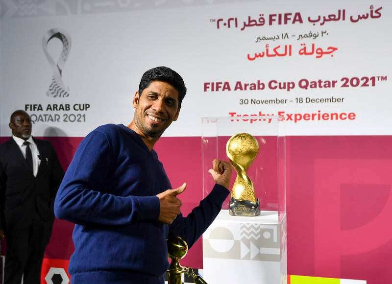 A man poses next to the Fifa Arab Cup Trophy.