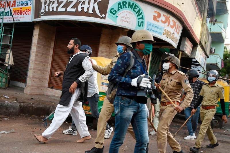 Gujarat Police personnel detain a man (L) as he participates in a stone pelting on police personnel in Shahpur area during a government-imposed nationwide lockdown as a preventive measure against the spread of the COVID-19 coronavirus in Ahmedabad on May 8, 2020.  Hundreds of paramilitary forces have been deployed in coronavirus-hotspot Gujarat state as India on May 8 faced a surge in the number of deaths and infections from the outbreak. / AFP / SAM PANTHAKY

