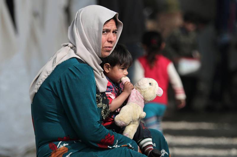 An internally displaced child carries a stuffed animal as he sits on a woman's lap at a makeshift camp in Afrin, Syria. REUTERS