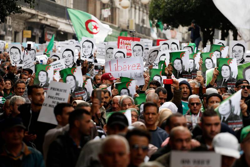 Protesters carry photos of political detainees as they take to the streets in the capital Algiers to reject the presidential elections and protest against the government, in Algeria, Friday, Dec. 27, 2019. (AP Photo/Toufik Doudou)