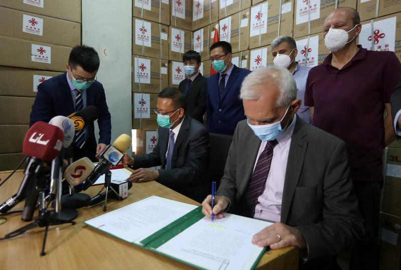 Deputy Syrian health minister, right, and Chinese ambassador to Syria Feng Biao, left, sign a document for receiving boxes of Chinese medical supplies at a store in Damascus, Syria.  EPA