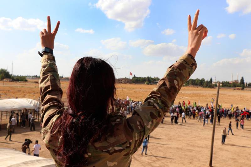 A fighter from the Syrian Democratic Forces, SDF, flashes the victory sign during a demonstration against possible Turkish military operation on their areas, at the Syrian-Turkish border, in Ras al-Ayn, Syria. AP Photo
