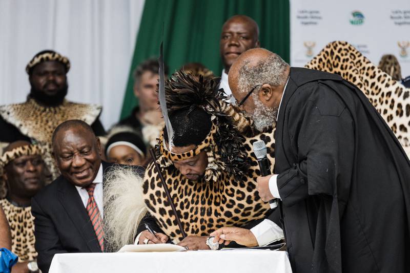 King Misuzulu Zulu, centre, flanked by South Africa's President Cyril Ramaphosa, left, signs final legal papers from acting KwaZulu-Natal Judge President Isaac Madondo during the coronation at the Moses Mabhida Stadium in Durban. AFP