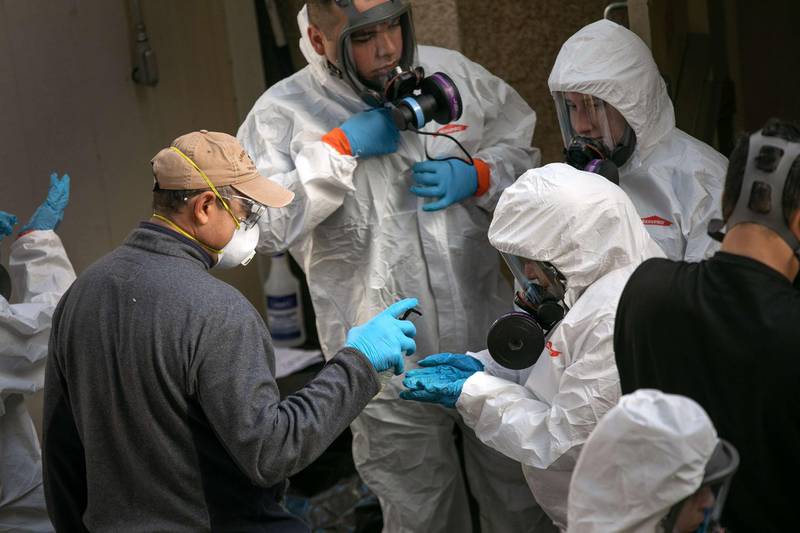 A cleaning crew disinfects and removes protective clothing after exiting the Life Care Center on March 11, 2020 in Kirkland, Washington. Getty Images/AFP