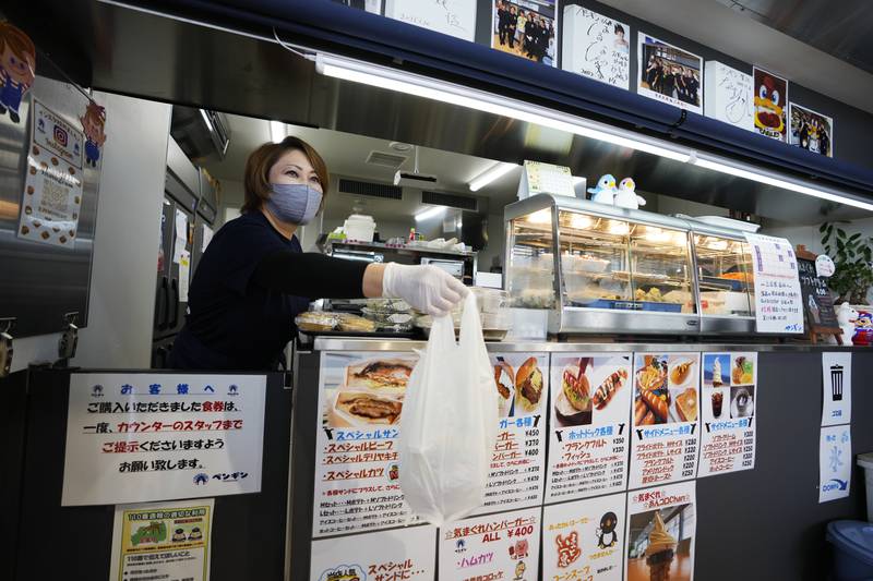 Fast-food restaurant owner Atsuko Yamamoto serves a customer at her shop, Penguin, in the town centre. The area only recently started to undergo reconstruction after the nuclear disaster and earthquake 11 years ago. AP