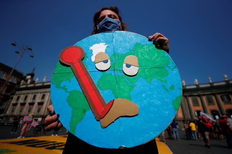 A person holds a placard depicting the Earth with a temperature.