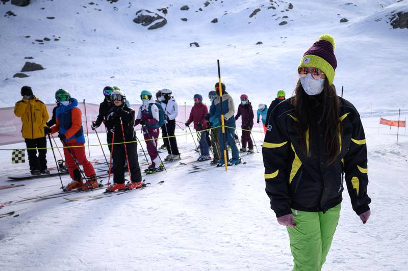 A staff member checks if skiers are wearing a protective face masks. AFP
