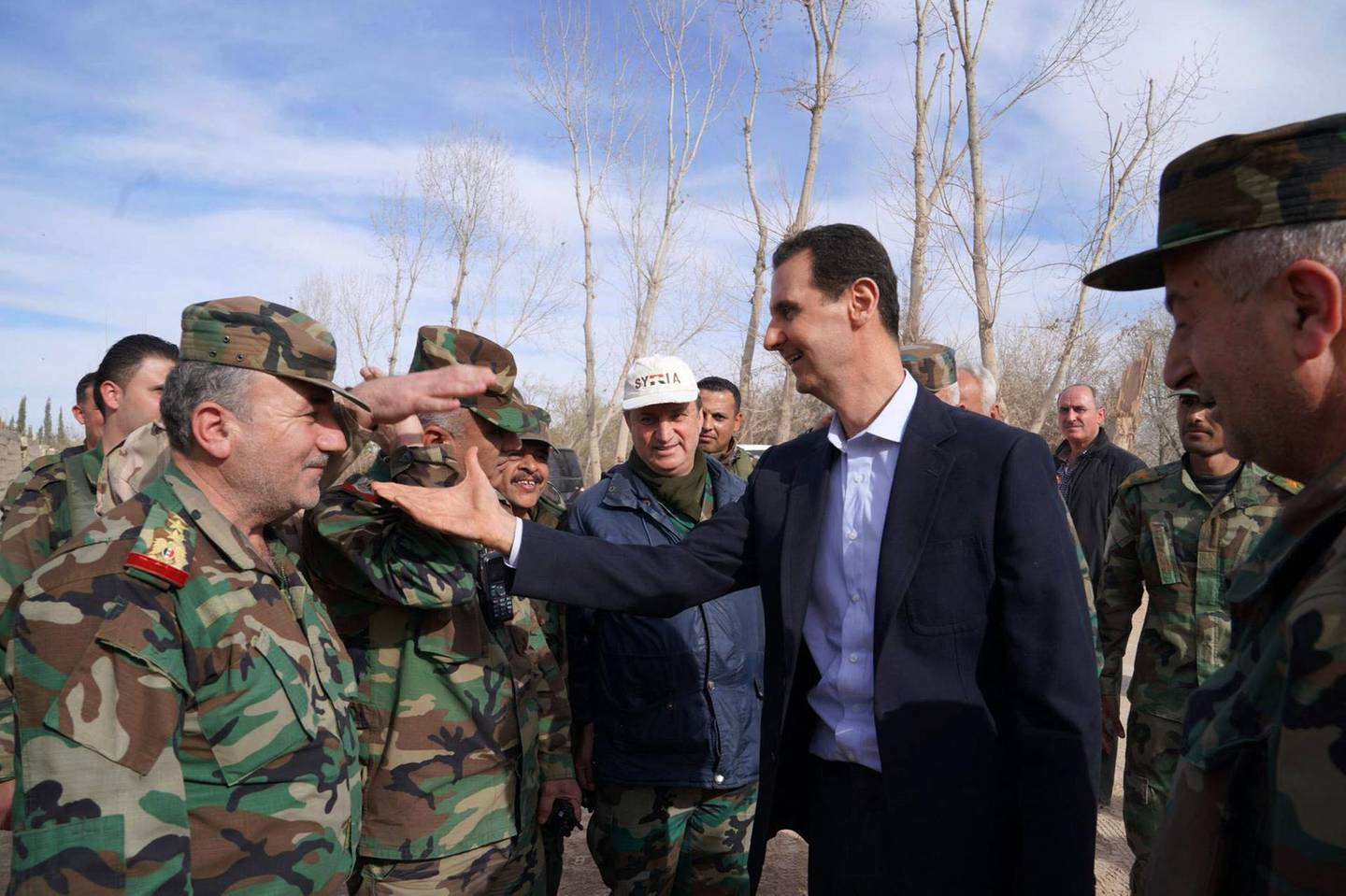 A handout picture released by the official Facebook page of the Syrian Presidency on March 18, 2018, shows Syrian President Bashar al-Assad (C) shaking hands with government troops in Eastern Ghouta, in the leader's first trip to the former rebel enclave outside Damascus in years. - Rebels have held out in Eastern Ghouta since 2012, but a regime assault in the last month has retaken more than 80 percent of the former opposition bastion, the Britain-based Syrian Observatory for Human Rights war monitor says. (Photo by HO / Syrian Presidency Facebook page / AFP) / RESTRICTED TO EDITORIAL USE - MANDATORY CREDIT "AFP PHOTO / HO / SYRIAN PRESIDENCY FACEBOOK PAGE" - NO MARKETING NO ADVERTISING CAMPAIGNS - DISTRIBUTED AS A SERVICE TO CLIENTS