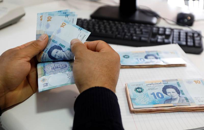 A man counts new 10 Dinar banknotes depicting the country's first woman doctor, Tawhida Ben Cheikh, in Tunis. Reuters