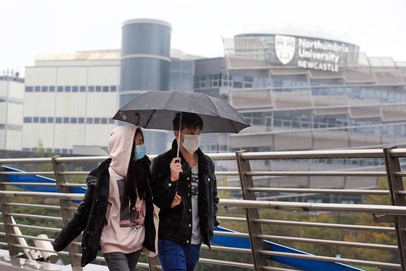 A couple wearing masks walk close to Northumbria University. AFP