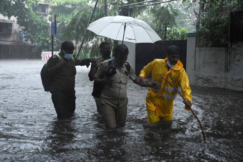An Indian policeman helps out on a flooded street in Mumbai after a bus broke down in heavy rain carried by cyclone Tauktae. EPA