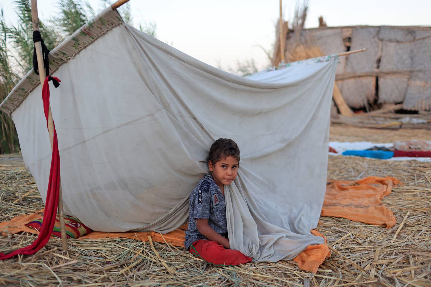 A child sits by his home at the Chebayesh marsh, Dhi Qar province, in Iraq, on August 15, 2021. Reuters