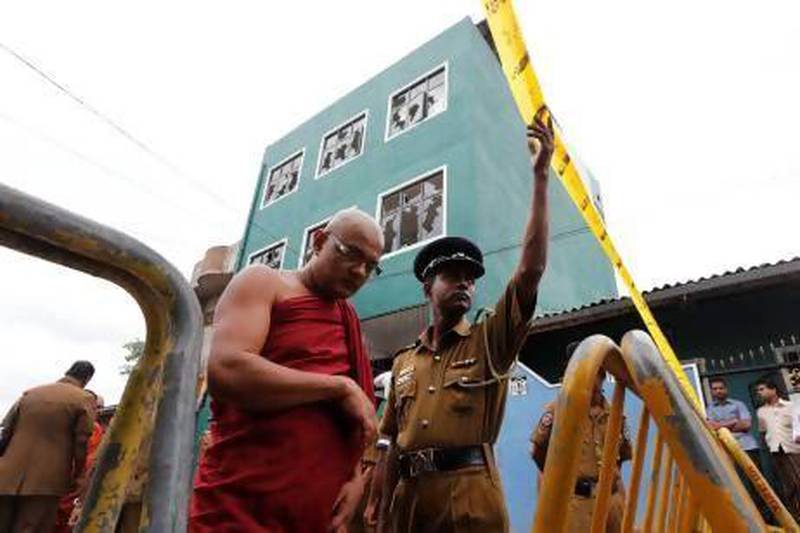 A Sri Lankan Buddhist monk walks past a vandalised mosque in Colombo as police man a barricade.