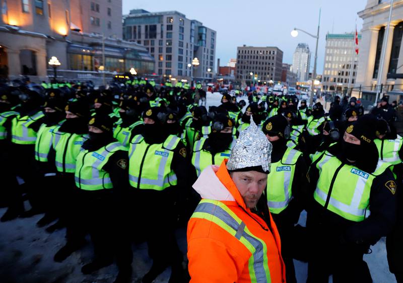 A demonstrator wears a tinfoil hat in front of a row of police. Reuters