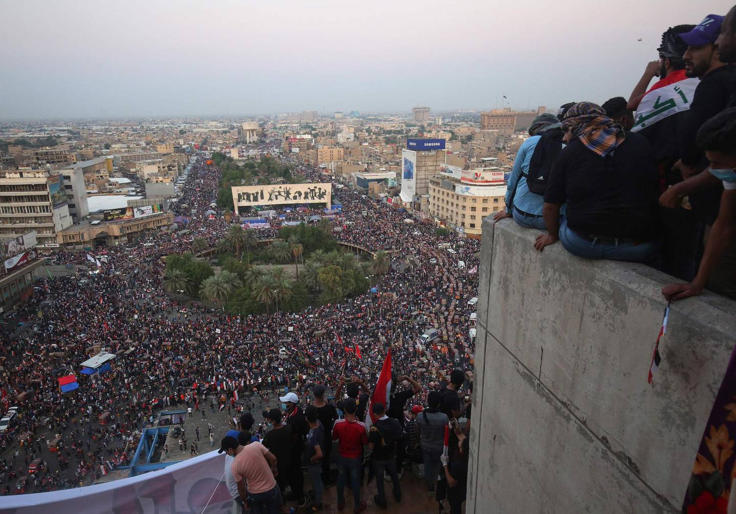 Iraqi demonstrators gather on several storeys of the  "Turkish restaurant"  an abandoned building in the capital Baghdad, overlooking the Tahrir square and the al-Jumhuriya bridge that leads to the high-security Green Zone, which hosts government offices and foreign embassies, during the ongoing anti-government protests on October 31, 2019. The "Turkish restaurant", a relic from the time of Saddam Hussein, has become the control tower of the revolt against power in Iraq. / AFP / AHMAD AL-RUBAYE
