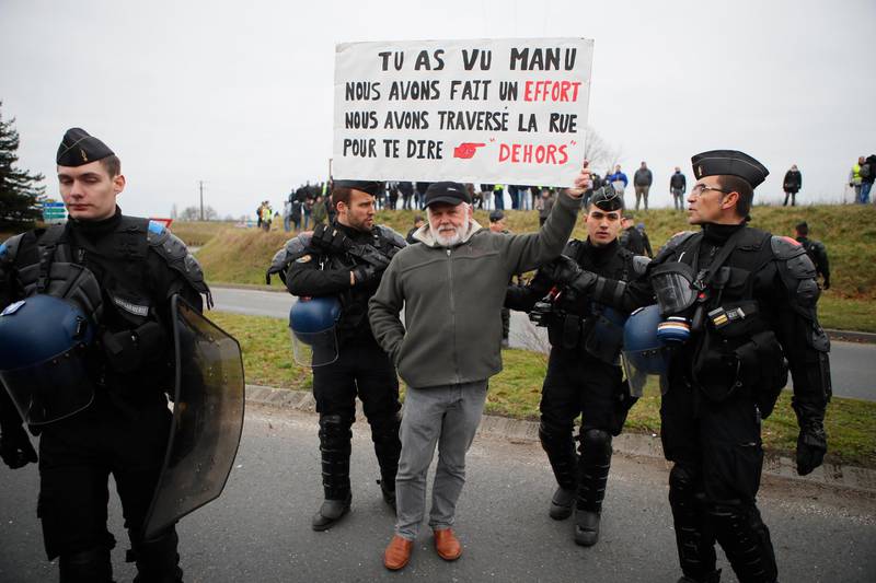 A protestor holds a poster reading "Emmanuel, we made an effort, we crossed the street to tell you, go away" before French President Emmanuel Macron's visit in Grand Bourgtheroulde, Normandy, Tuesday, Jan.15, 2019. Macron is formally launching a "grand debate" to try to appease the yellow vest movement following weeks of anti-government protests. (AP Photo/Francois Mori)