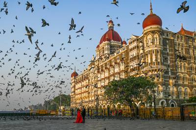 A couple poses for photographs in front of the Taj Mahal hotel in Mumbai on March 4, 2021. (Photo by Punit PARANJPE / AFP)