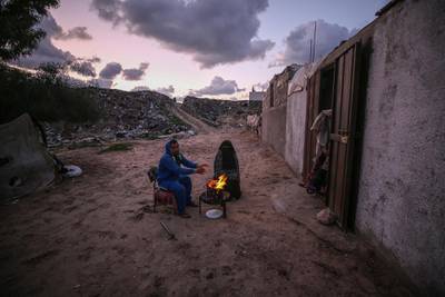 epa08149012 A couple warms themselves by a fire near their makeshift family house during cold weather in the south of Khan Younis Refugee Camp, Gaza Strip, 21 January 2020. More than 100 Palestinian families live in a devastating and an impoverished area, known as Nahr Al-Barid, and they do not have any source of income. Reports from human rights institutions state that more 70 percent of Gaza's population is living below the poverty line, set under international standards.  EPA/MOHAMMED SABER