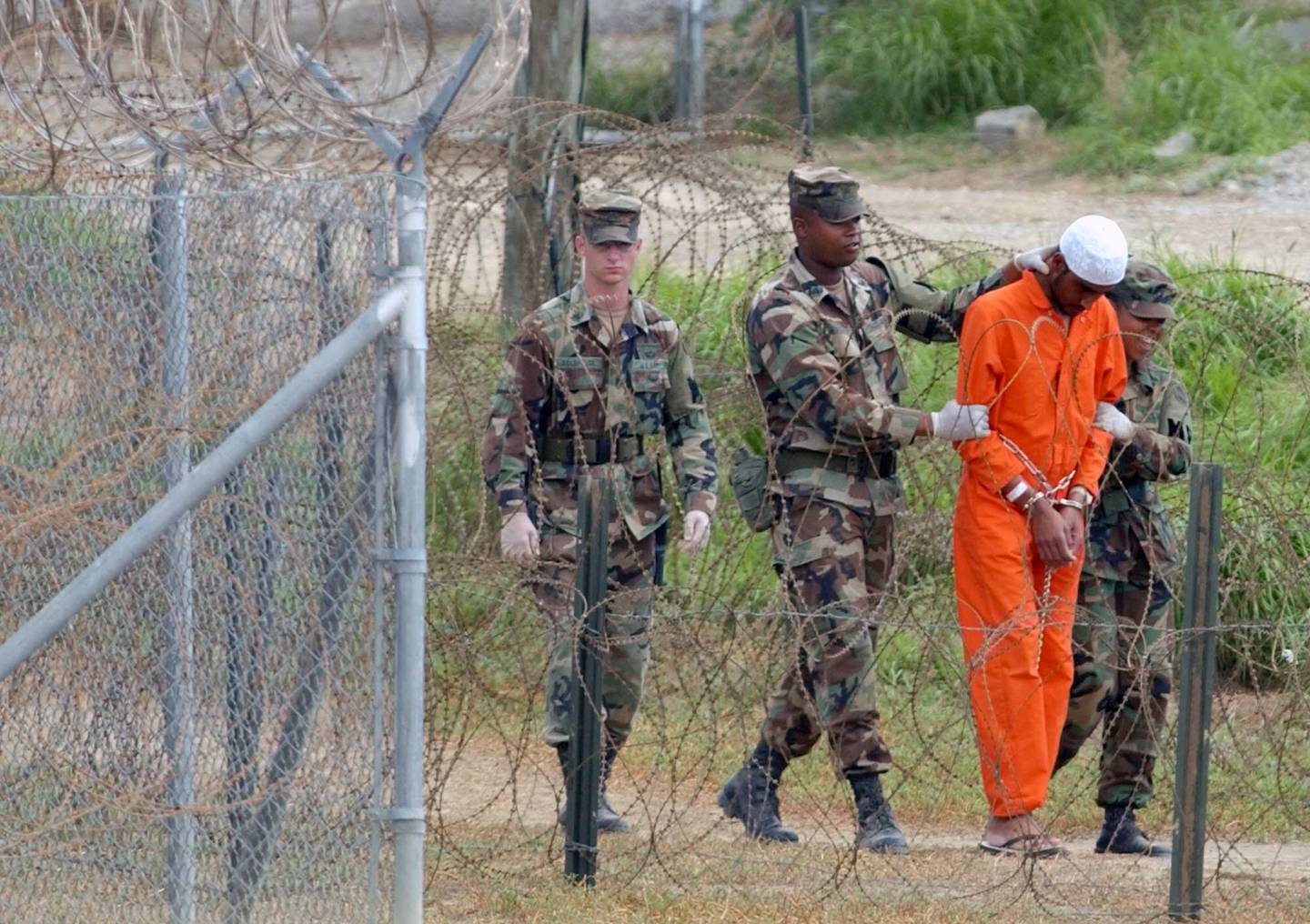 In this February 6, 2002, file photo a detainee is led by military police to be interrogated by military officials at Camp X-Ray at the US Naval Base at Guantanamo Bay, Cuba. AP