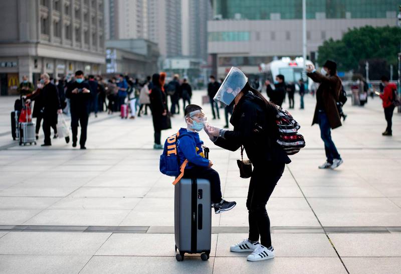 A woman adjusts her child's mask as they arrive at Hankou Railway Station in Wuhan.  AFP