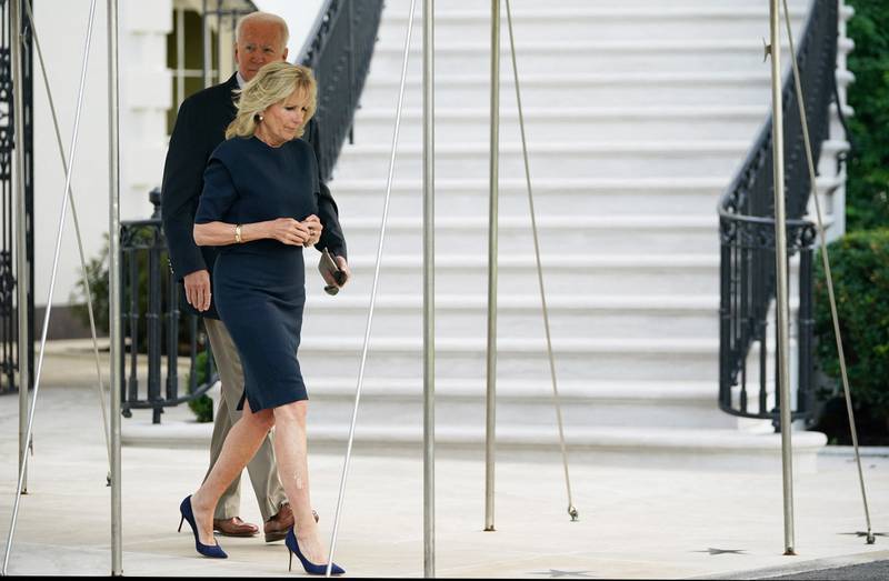 Jill Biden, in a navy shift dress, and President Joe Biden walk the White House South Lawn on July 1, 2021. AFP