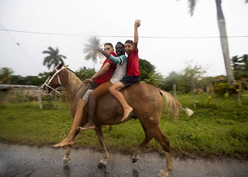 People on a horse wave in the streets of Coloma, a town through which Hurricane Ian is expected to enter, in Pinar del Rio province, Cuba. EPA