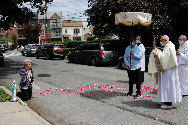 Deacon Robert Lavanco of Our Lady of Hope Catholic Church, prays with Krystyna Kopacki as she kneels in the street during a procession called the Blessed Sacrament, to bring blessings to worshippers outside their homes while their church sanctuary is closed to them in the Queens borough of New York City. Reuters