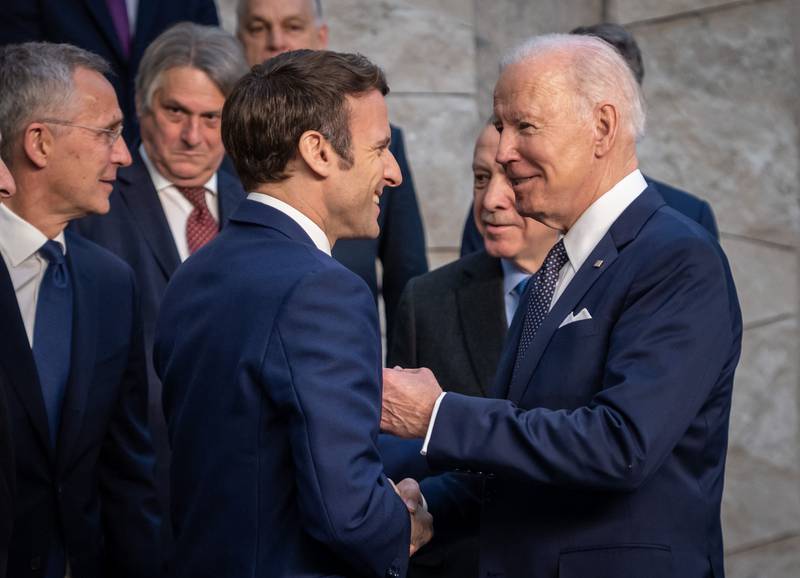 France's President Emmanuel Macron shakes hands with Mr Biden as they arrive at Nato headquarters. AFP