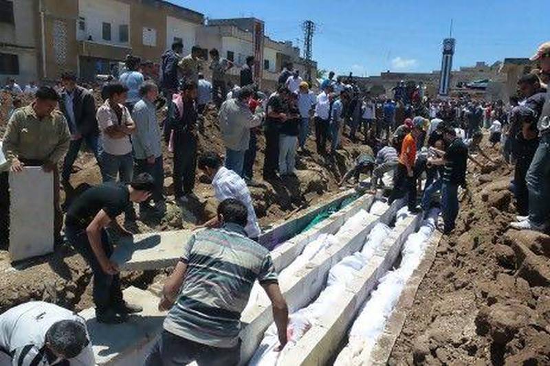 People watch a mass burial of more than 100 Sunni villagers killed in the central Syrian city of Houla in a massacre condemned globally.