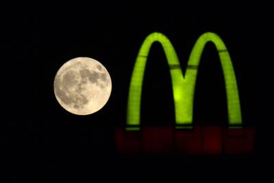 A sturgeon supermoon rises beside a McDonald's logo in Jalandhar, India. AFP