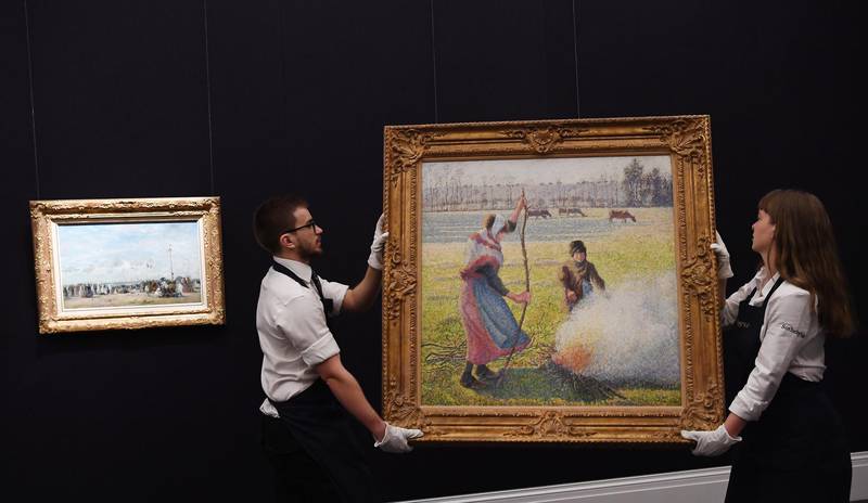 epa08175759 Sotheby's staff with Camille Pissarro's  'Gelee blanche, jeune lausanne faisnat du feu' (1888) during Sotheby's impressionist, modern, surrealist art sale in London, Britain, 29 January 2020. The painting is estimated to fetch between US$10-15 million at auction Feb 04.  EPA/ANDY RAIN