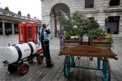 A worker waters flowers in Covent Garden as preparations are made ahead of shops re-opening in London. AP Photo