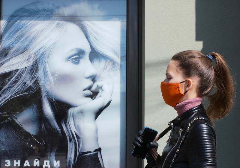 FILE PHOTO: A woman wearing a protective face mask amid the outbreak of the coronavirus disease (COVID-19) walks near an advertising poster in Kiev, Ukraine June 3, 2020. REUTERS/Gleb Garanich/File Photo