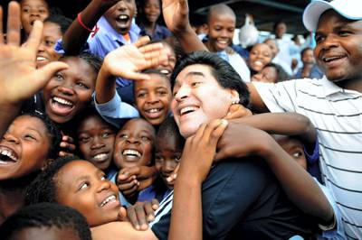WINTERVELDT, SOUTH AFRICA - JANUARY 19:  In this handout photo provided by 2010 FIFA World Cup Organising Committee South Africa, Argentina national soccer team's head coach Diego Maradona is greeted by schoolchildren during his visit to Kgotlelelang School at Winterveldt on January 19, 2010, around 40km north west of Pretoria, South Africa.  (Photo by 2010 FIFA World Cup Organising Committee South Africa via Getty Images)