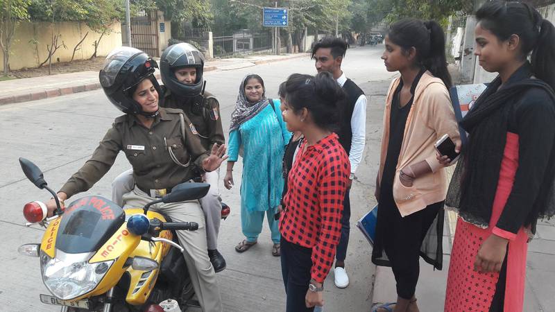 Delhi police constables Sushila Meena, front, and Manju Devi stop to chat to students while returning from a training session for a new motorcycle patrol squad in the Indian capital on November 25, 2017. Amrit Dhillon for The National