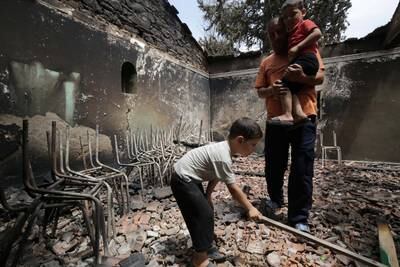 A man and his children inspect the damage to their house after a fire raced through the Algerian village of De Oeud Das. EPA