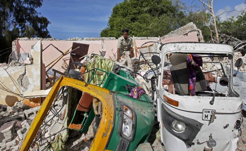 A member of Somalia's security forces walks past destroyed vehicles at the scene of a car bomb blast and gun battle targeting a restaurant in Mogadishu, Somalia on June 15, 2017. Somali survivors described harrowing scenes of the night-long siege of a popular Mogadishu restaurant by Al Shabab Islamic extremists that was ended by security forces. Farah Abdi Warsameh/AP Photo