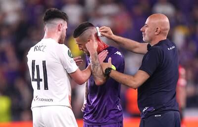Fiorentina's Cristiano Biraghi receives treatment for a cut caused by an object thrown from the crowd as West Ham's Declan Rice checks he is OK. PA 