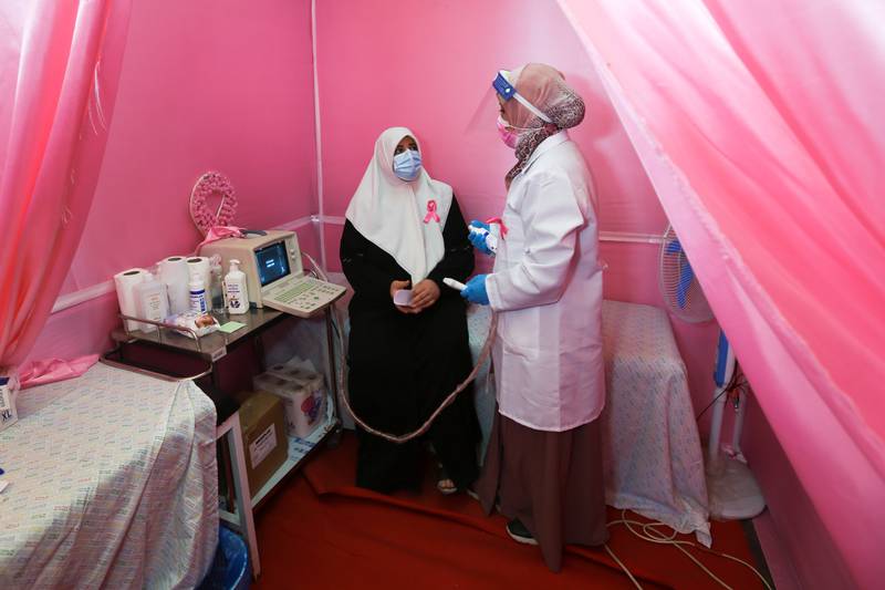 A Palestinian doctor prepares a woman for a breast cancer check-up inside a mobile clinic set up in a lorry.