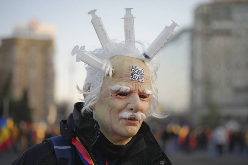 A protester wears a latex mask with syringes attached to it during a rally in front of the government headquarters in Bucharest, Romania. Marchers object to a Covid-19 ‘green certificate’ in workplaces to limit infections. AP