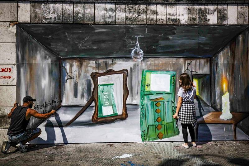 (FILES) In this file photo taken on July 8, 2020 (L to R) Palestinian-Syrian artist Ghayath al-Roubeh and Lebanese artist Nagham Abboud paint together a graffiti mural depicting a 100,000 Lebanese pound banknote being reflected in a mirror as a 1000 Lebanese pound note, symbolising the level of inflation caused by the shrinking Lebanese economy, at al-Nour Square in Lebanon's northern port city of Tripoli. For months, Lebanon has grappled with its worst economic crisis since the 1975-1990 civil war.
Tens of thousands have lost their jobs or part of their salaries, while a crippling dollar shortage has sparked rapid inflation.
 - RESTRICTED TO EDITORIAL USE - MANDATORY MENTION OF THE ARTIST UPON PUBLICATION - TO ILLUSTRATE THE EVENT AS SPECIFIED IN THE CAPTION
 / AFP / Ibrahim CHALHOUB / RESTRICTED TO EDITORIAL USE - MANDATORY MENTION OF THE ARTIST UPON PUBLICATION - TO ILLUSTRATE THE EVENT AS SPECIFIED IN THE CAPTION
