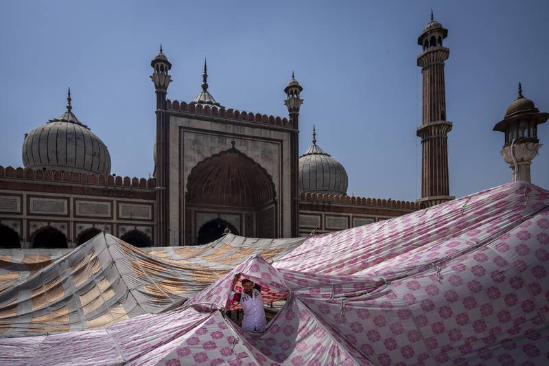 A man looks through a sunshade tent erected for worshippers in the compound of Jama Masjid in New Delhi, India. AP